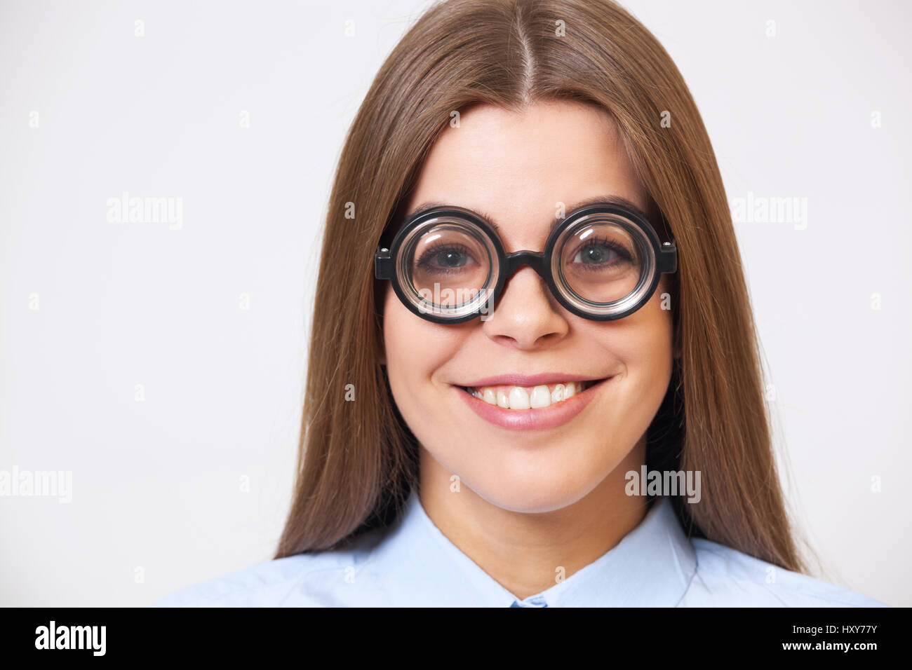 Studio-Porträt der lustige glückliche junge Geschäftsfrau in großen Nerd-Brillen auf grauem Hintergrund. Stockfoto