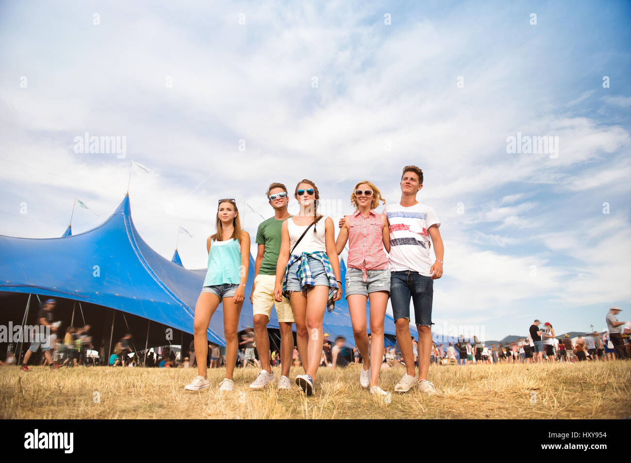 Gruppe von Teenager-Jungen und Mädchen im Sommer-Musikfestival zu Fuß vor der große blaue Zelt, sonnigen Tag Stockfoto