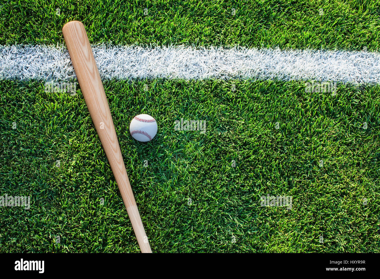 Ein Baseball-Schläger und Ball sitzen auf einer Wiese mit weißen Streifen von oben gesehen Stockfoto