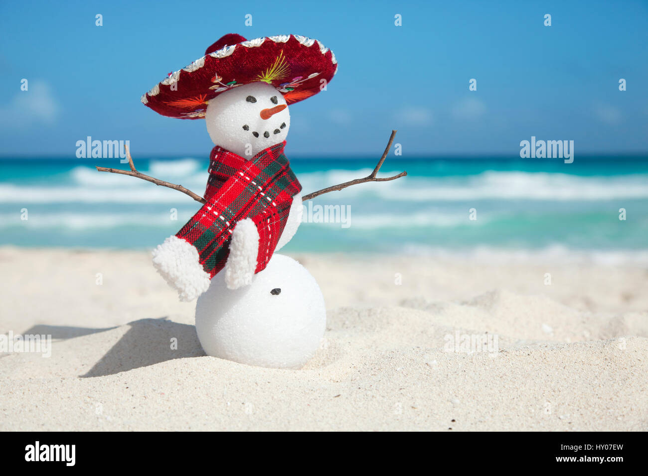 Miniatur-Schneemann trägt mexikanischen Sombrero und Schal am Strand von Cancun Stockfoto