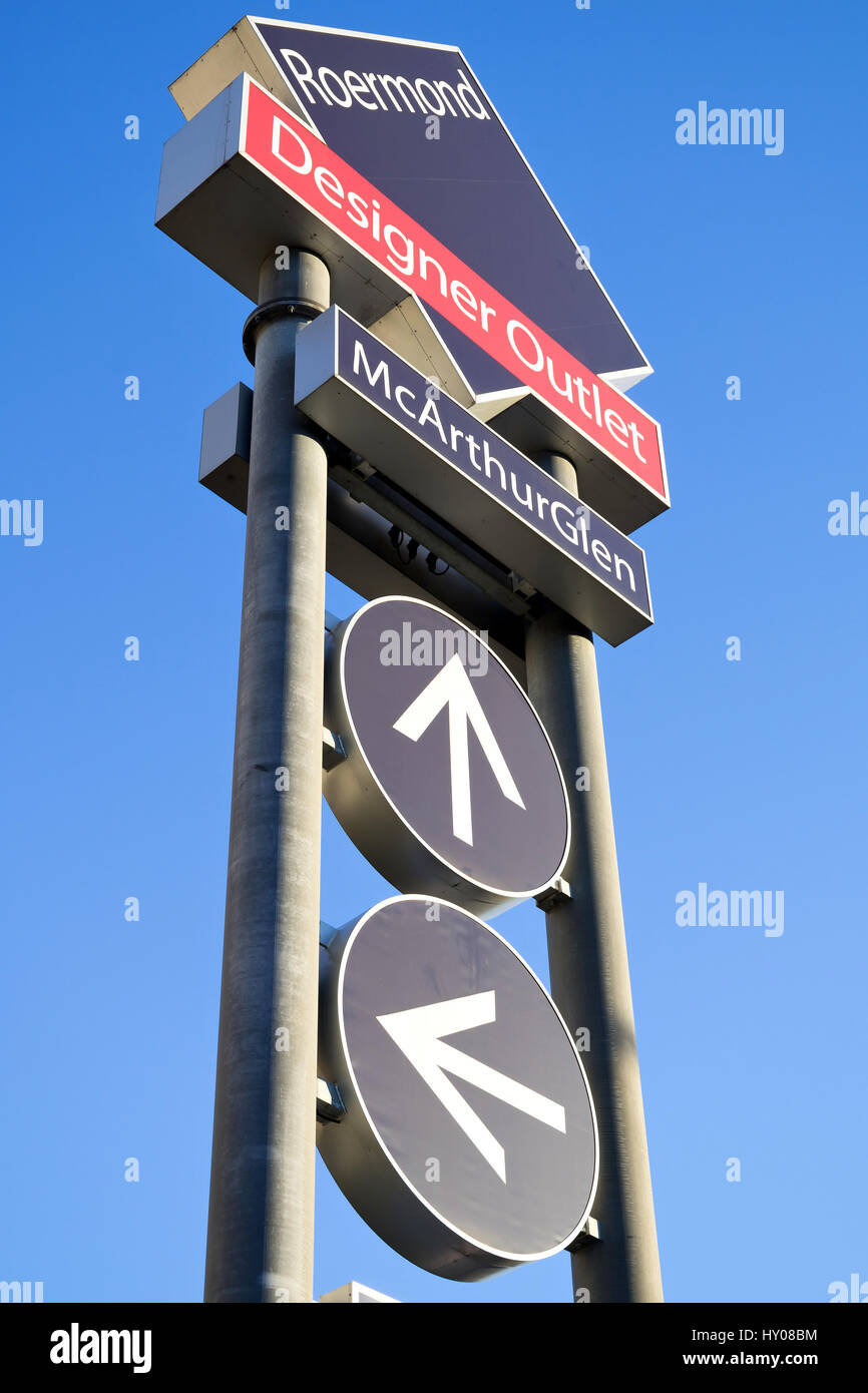 Wegweiser der McArthurGlen Designer Outlet in Roermond / NL gegen blauen Himmel.  McArthurGlen verwaltet derzeit 22 Designer Outlets in 9 Ländern. Stockfoto