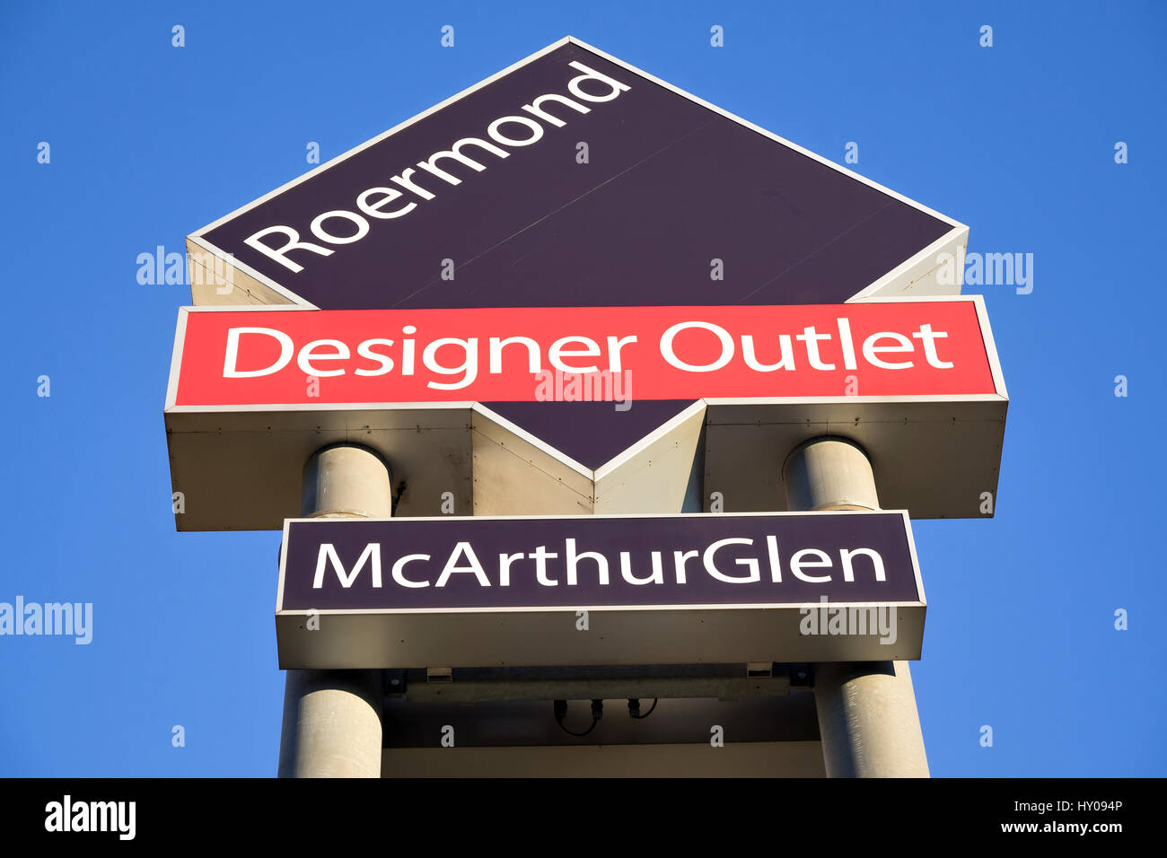 Wegweiser der McArthurGlen Designer Outlet in Roermond / NL gegen blauen Himmel.  McArthurGlen verwaltet derzeit 22 Designer Outlets in 9 Ländern. Stockfoto