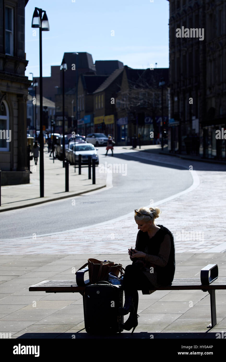 Frau saß auf einer Bank im Zentrum Stadt, Huddersfield Town centre eine große Marktstadt metropolitan Borough Kirklees, West Yorkshire, England. VEREINIGTES KÖNIGREICH. Stockfoto