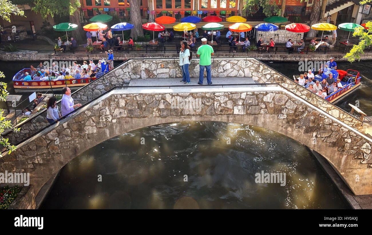 Touristen, die über eine Brücke an der San Antonio River Walk als Tourenboot geht unter in San Antonio, Texas Stockfoto
