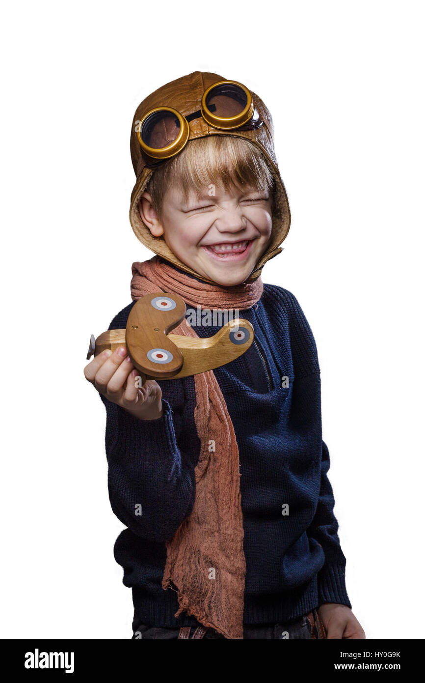 Glückliches Kind gekleidet in pilot Hut und Brille. Kind spielen mit Holzspielzeug Flugzeug. Traum und Freiheit Konzept. Retro. Studio Portrait isoliert weiß Stockfoto