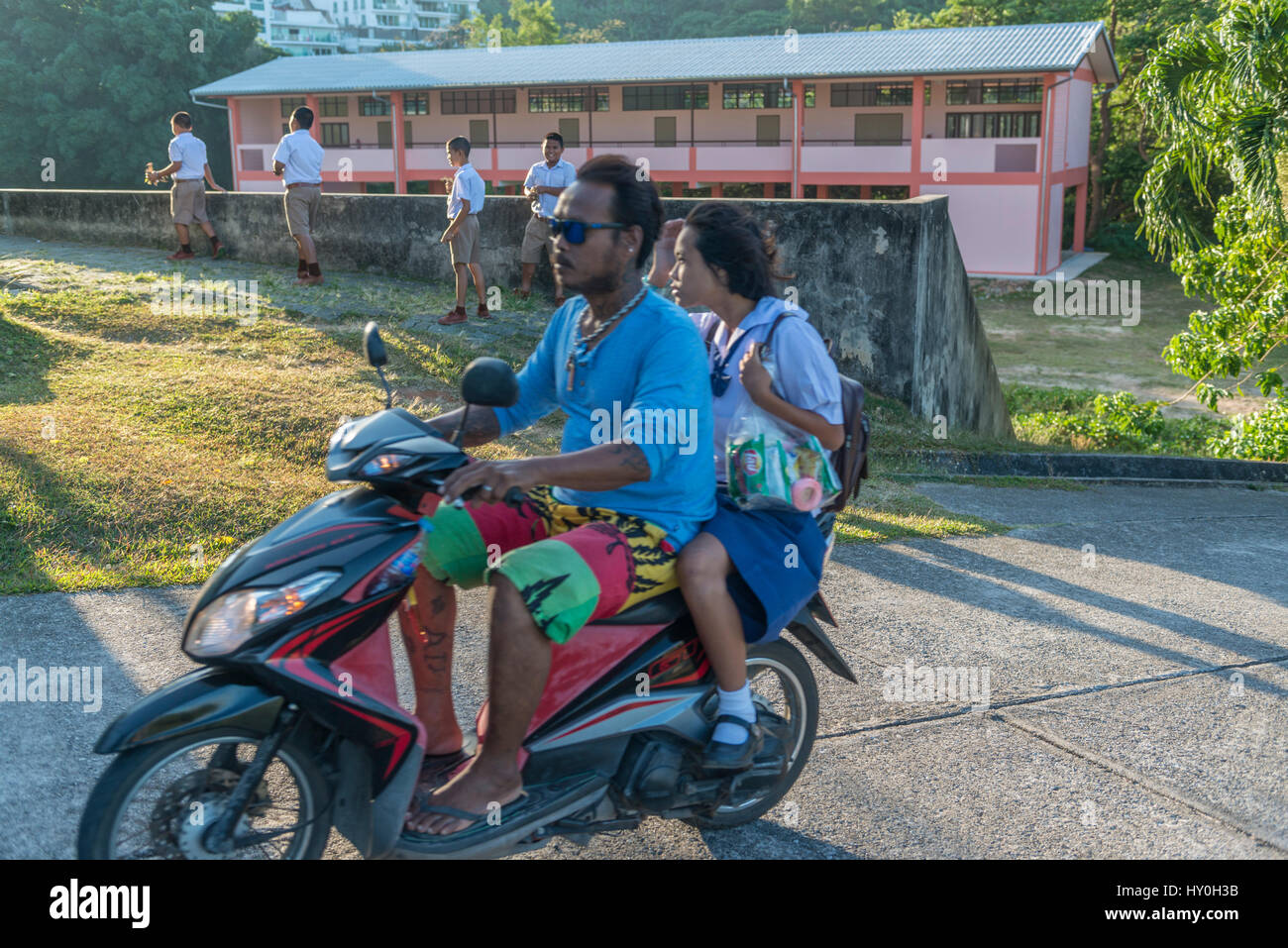 Ein Vater nimmt seine Tochter zur Schule mit dem Motorrad in den frühen Morgenstunden in Phuket, Thailand. 10. März 2017 Stockfoto