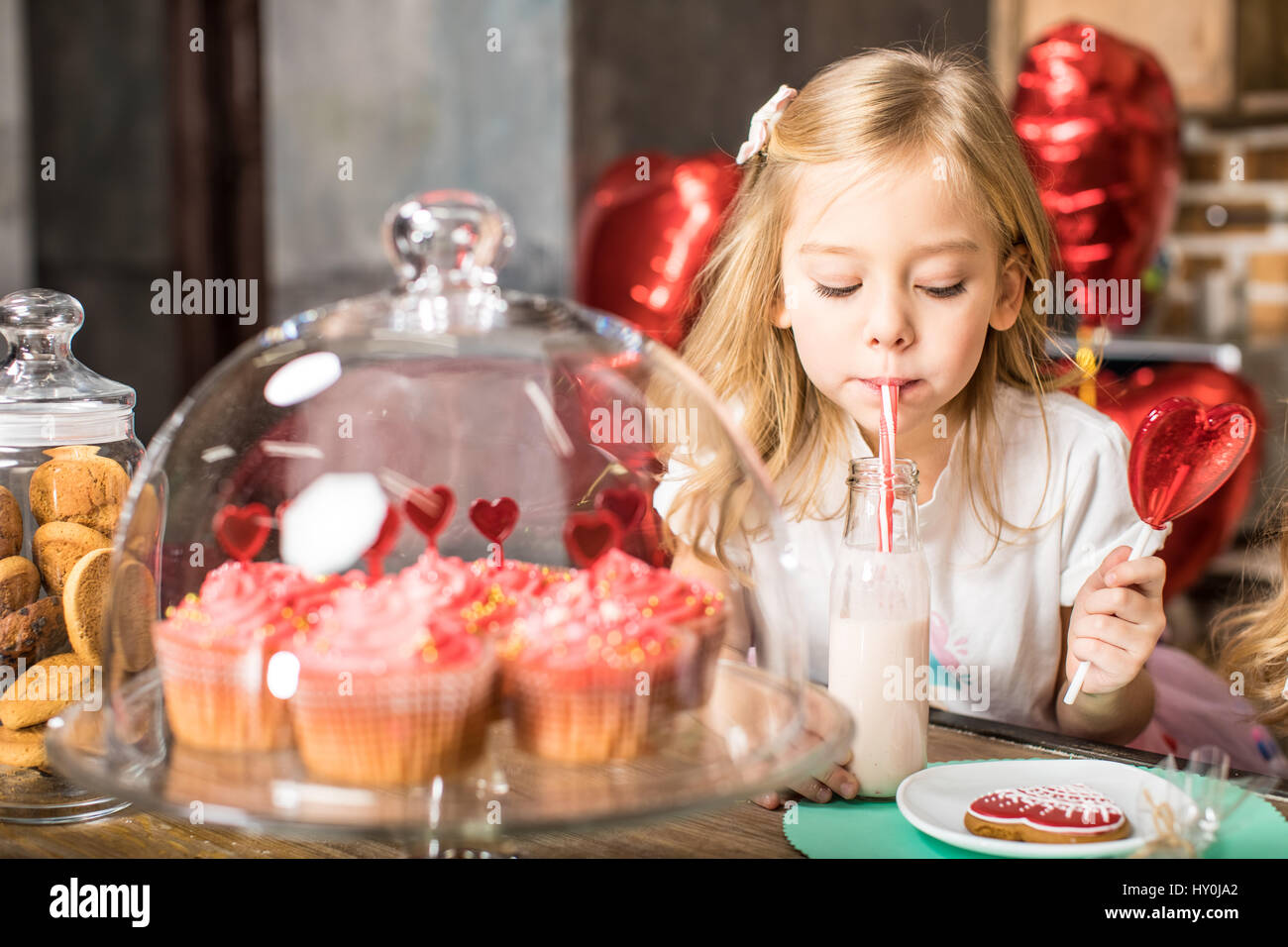 Kleines Mädchen auf Geburtstagsparty Milchshake aus Glasflasche trinken Stockfoto