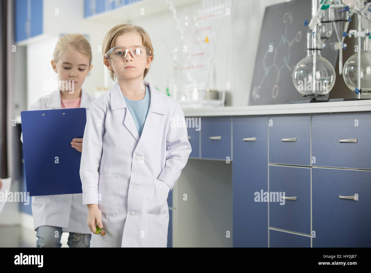 Schulkinder in Laborkittel studieren im chemischen Labor Stockfoto