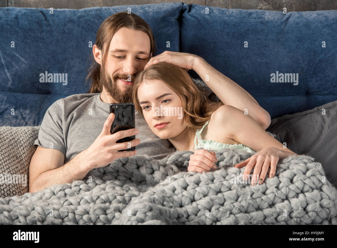 Junges Paar im Bett liegend und halten Fernbedienung Stockfoto