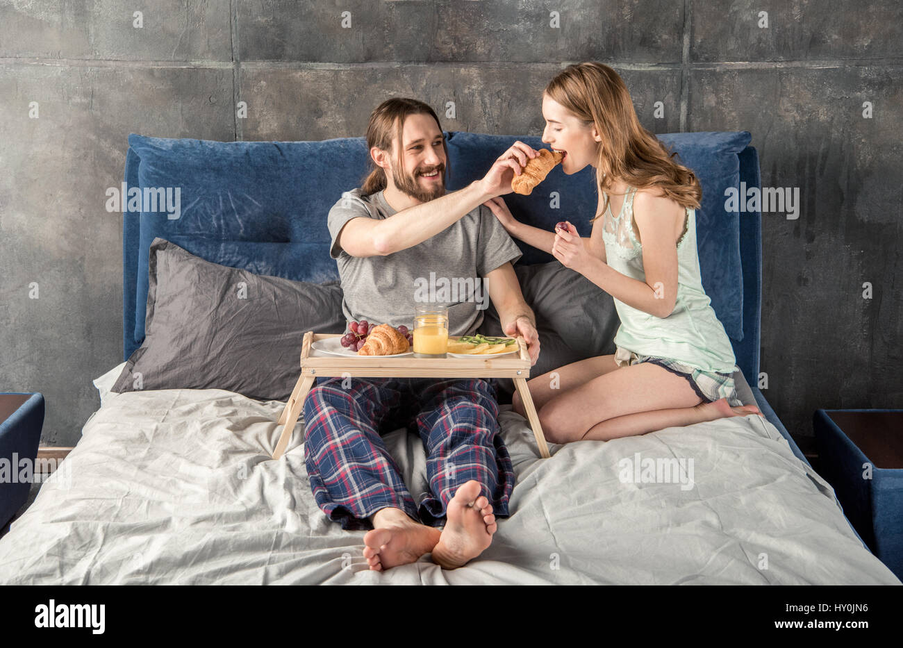 Junge Frau füttert ihr Freund mit Frühstück im Bett Stockfoto