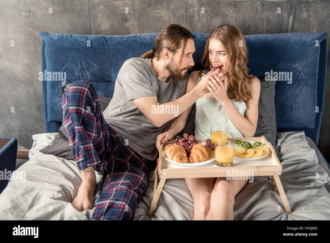 Mann, die Fütterung seiner Freundin während sie im Bett liegend Stockfoto