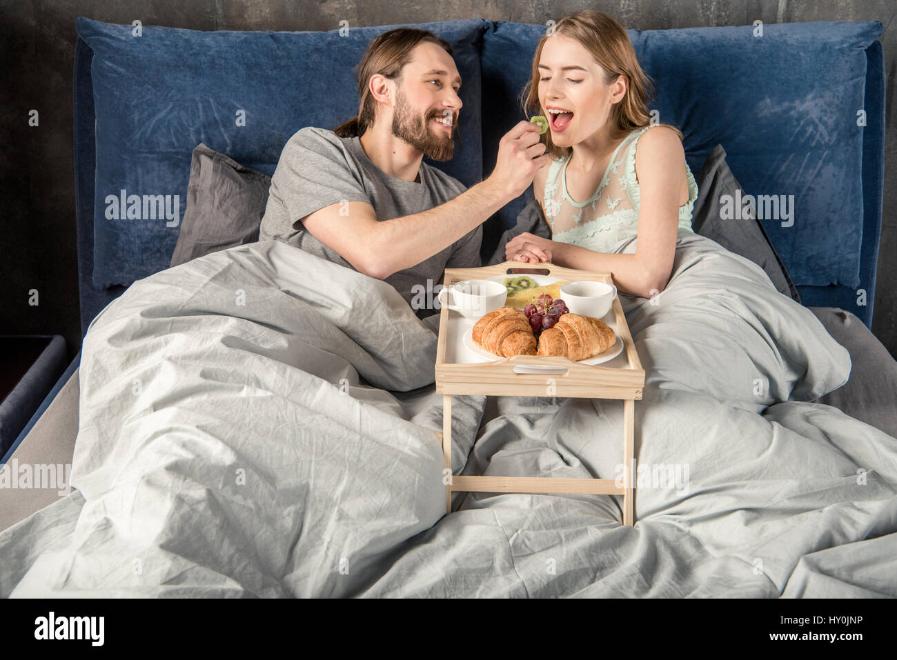 Junger Mann seine Freundin mit einem Frühstück im Bett Fütterung Stockfoto