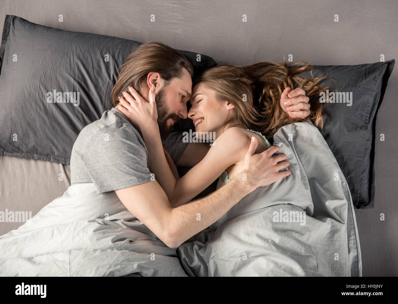 Junges Paar lächelnd und sahen einander beim liegen im Bett Stockfoto