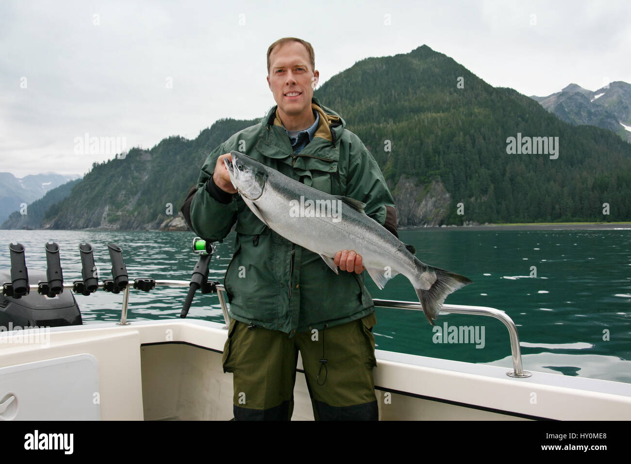 Ein glücklicher Fischer in Alaska hält ein frisch gefangener Silberlachs Stockfoto