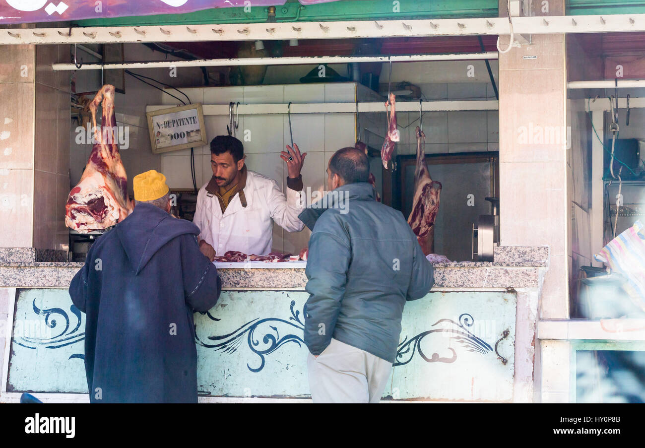 Traditionelle Metzgerei in Marrakesch Straße mit hängendes Fleisch, Rindfleisch, Lamm mit Verkäufer und Kunden Stockfoto