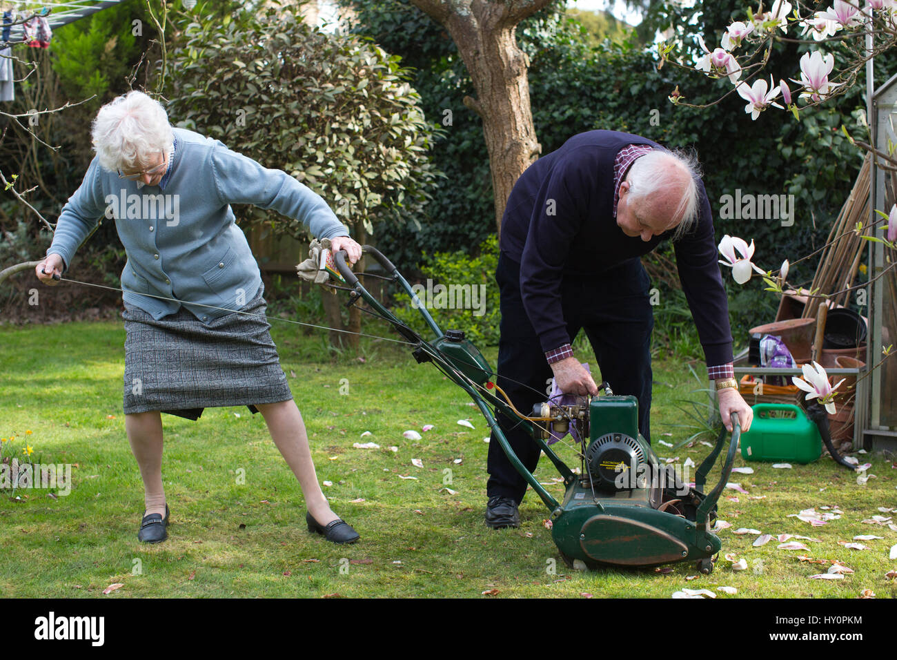 Rentner, die versuchen, starten Sie einen Benzin-Rasenmäher in einem  englischen Wohn Garten auf einer Feder Nachmittag, Surrey, England,  Vereinigtes Königreich Stockfotografie - Alamy