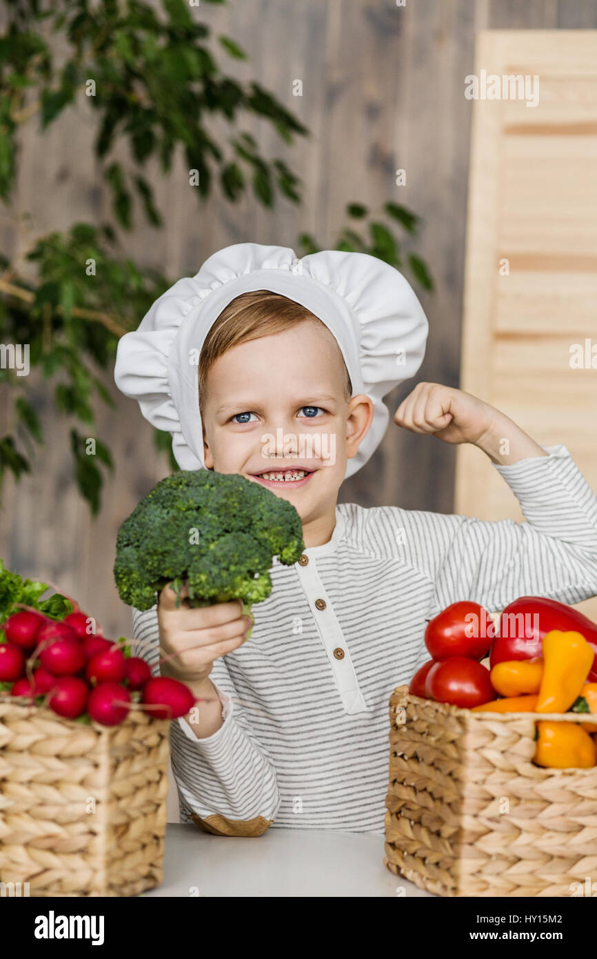 Gut aussehend Geißlein in uniform mit Gemüse Chef. Kochen in der Küche zu Hause. Vegetarier. Gesunde Ernährung Stockfoto