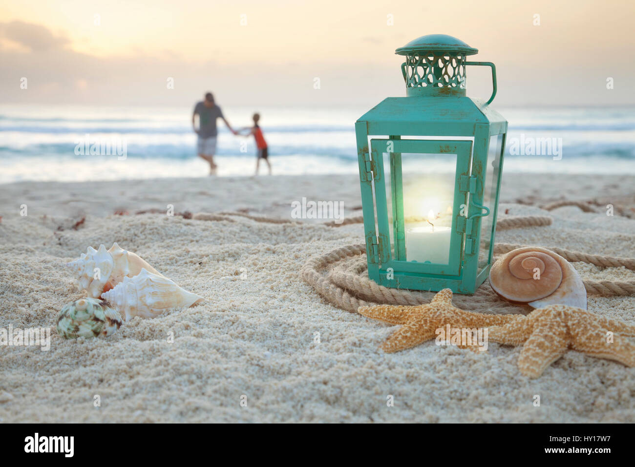Laterne mit Muscheln am Strand mit soft-Focus-Vater und Sohn sammeln von Muscheln im Hintergrund bei Sonnenaufgang Stockfoto