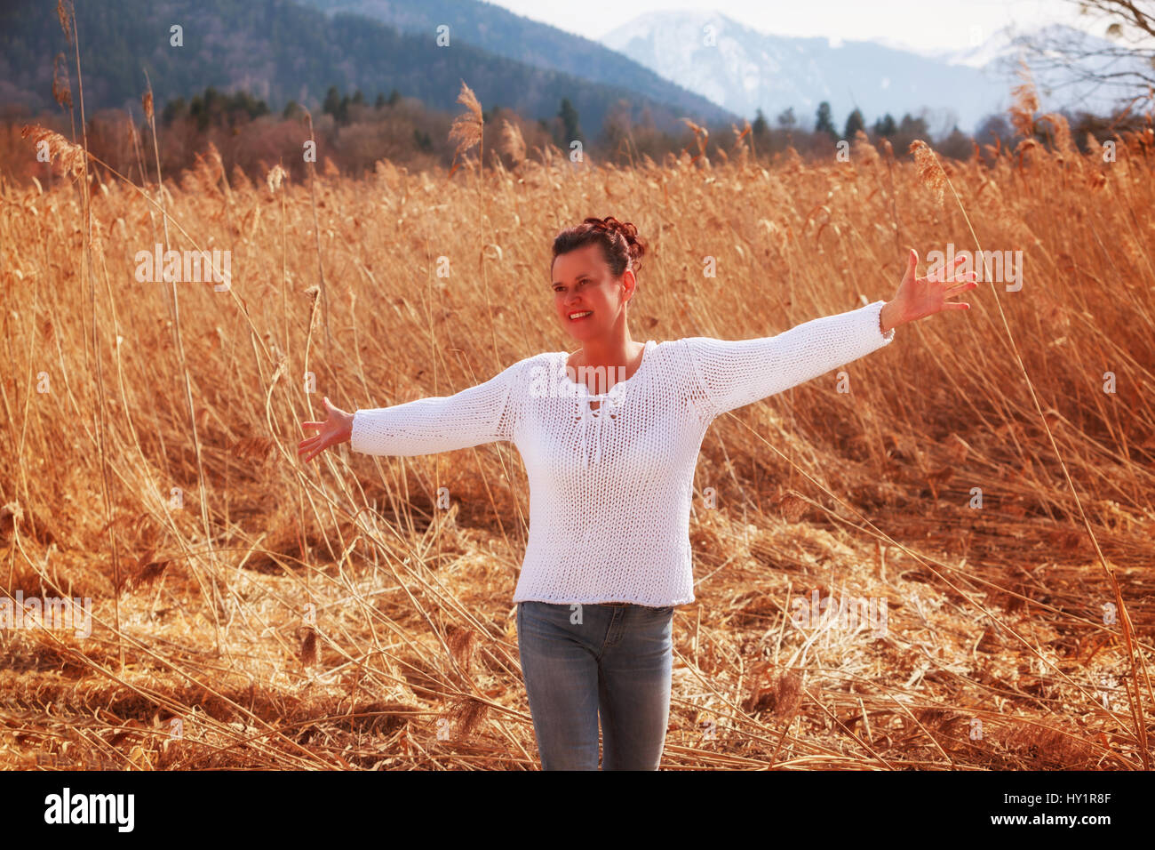 Frau im besten Alter steht in einem Schilfgürtel und freut sich auf den Frühling. Stockfoto