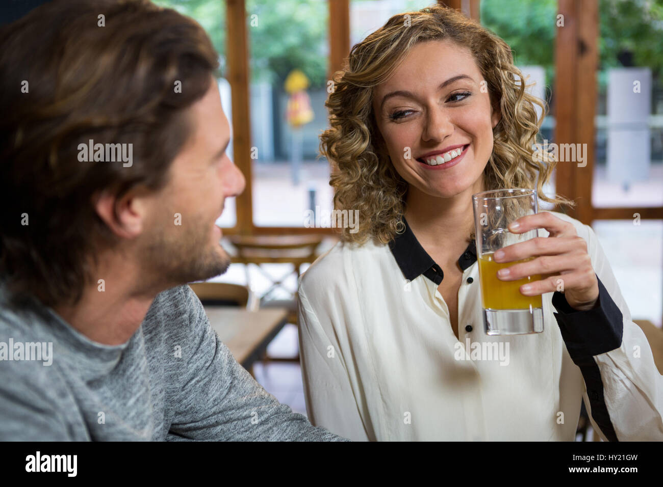 Lächelnde junge Frau mit Saft beim betrachten Mann im Café Stockfoto