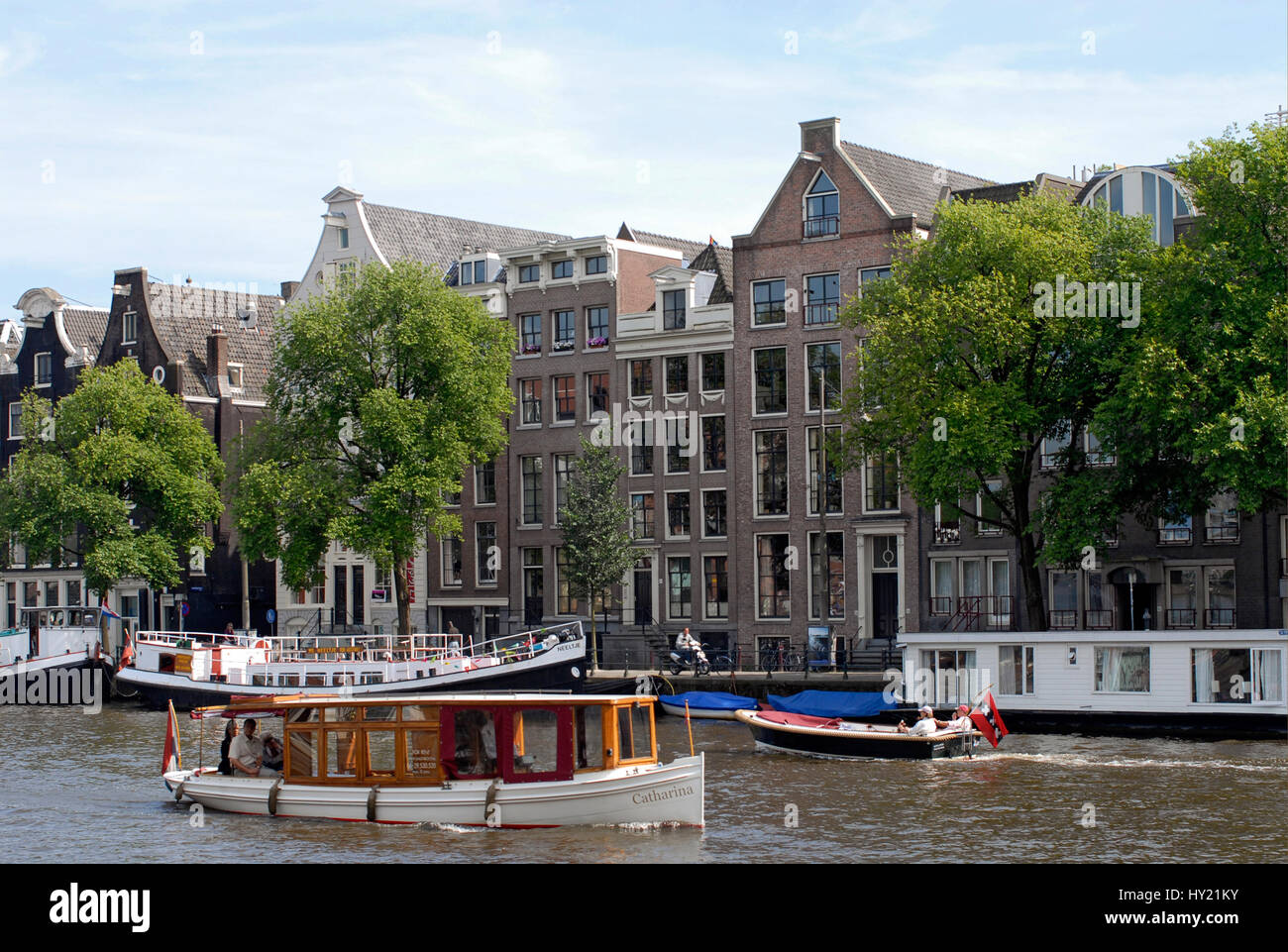 Typische Sightseeing-Boote in einem Wasserkanal in das Stadtzentrum von Amsterdam, Niederlande. Stockfoto