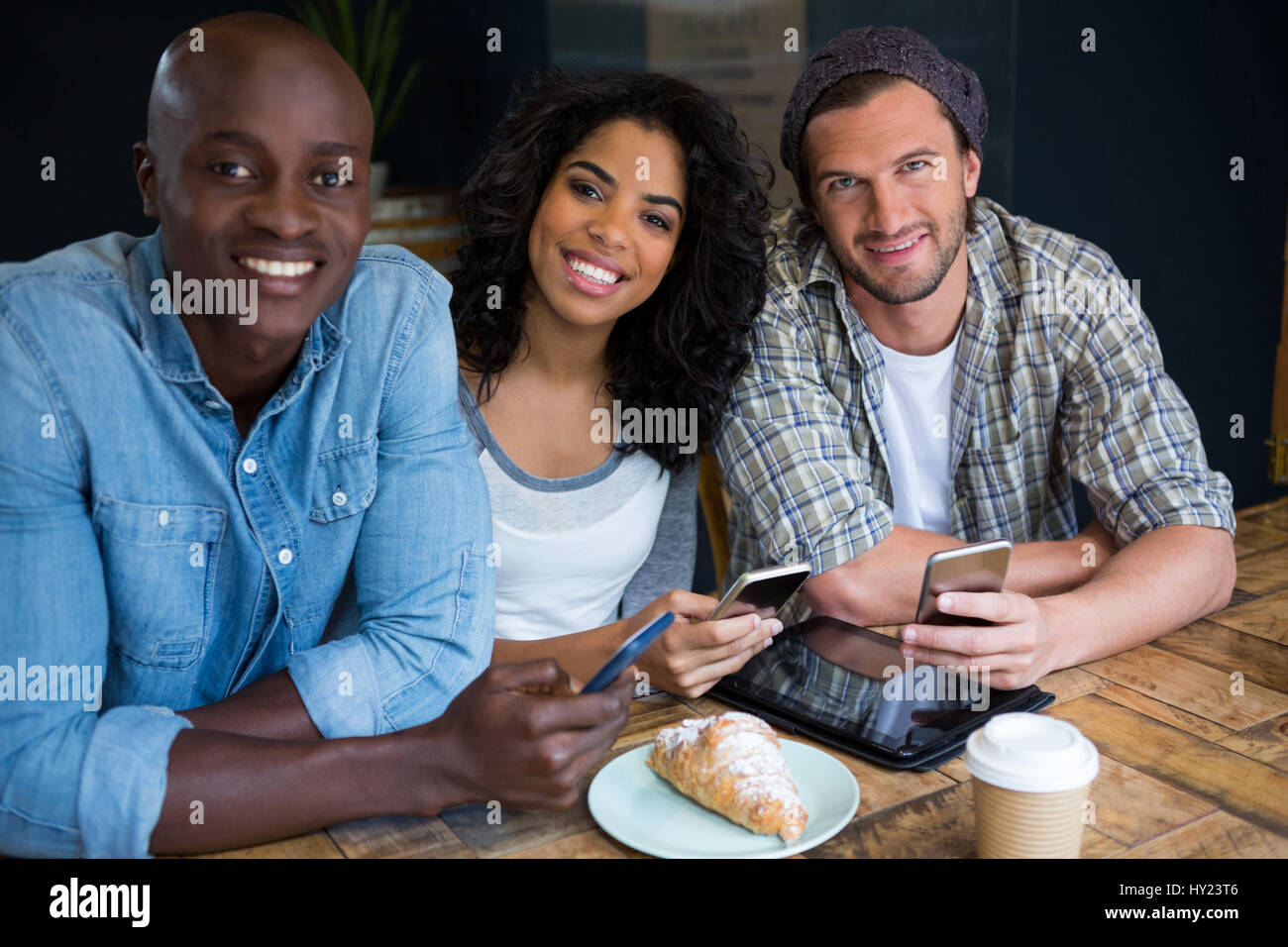 Porträt von lächelnden jungen Freunde halten Smartphones am Tisch im Café Stockfoto