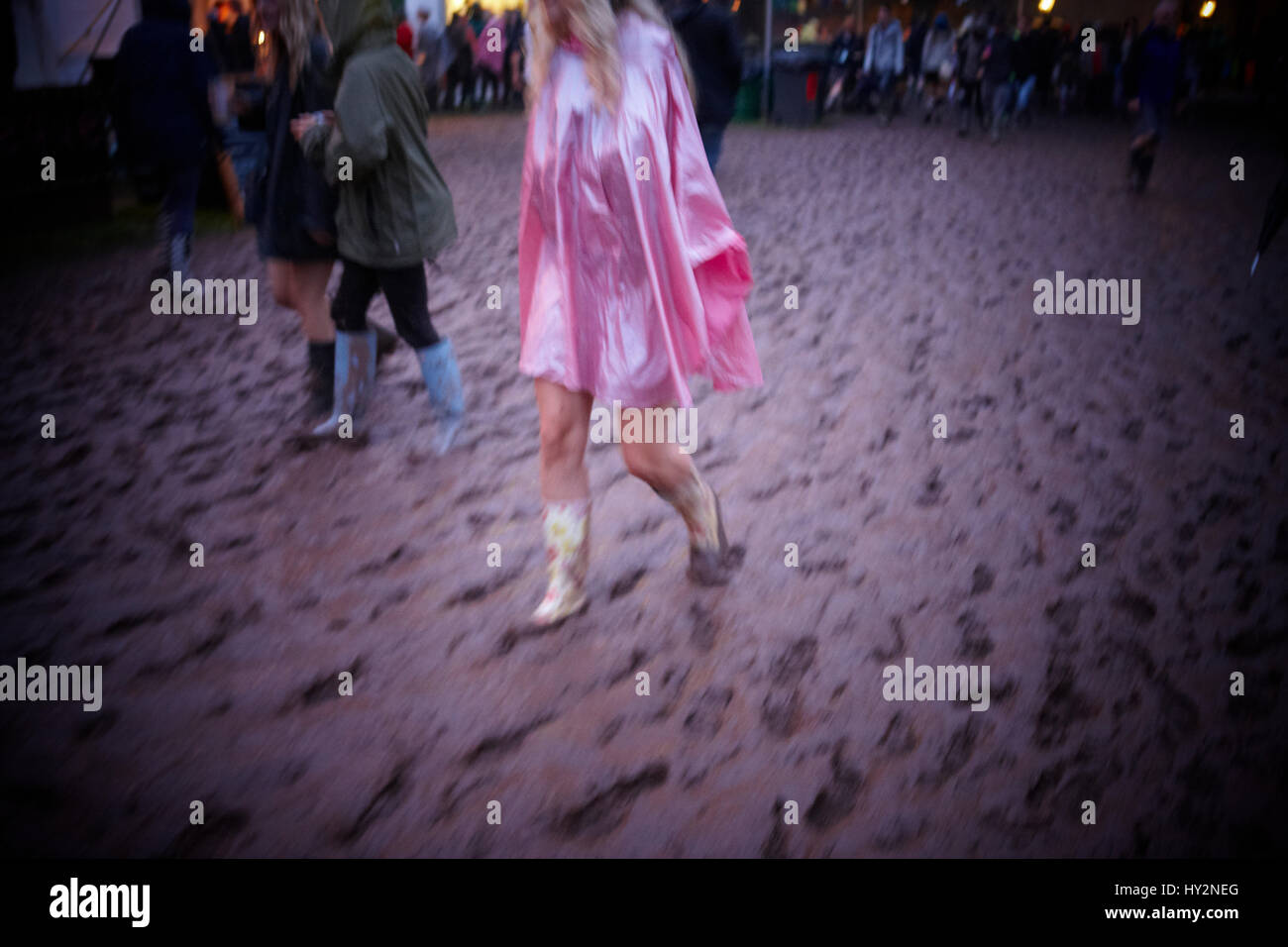 Frau trägt einen rosa Poncho geht durch den Schlamm auf dem Grren Mann Festival, Wales Stockfoto