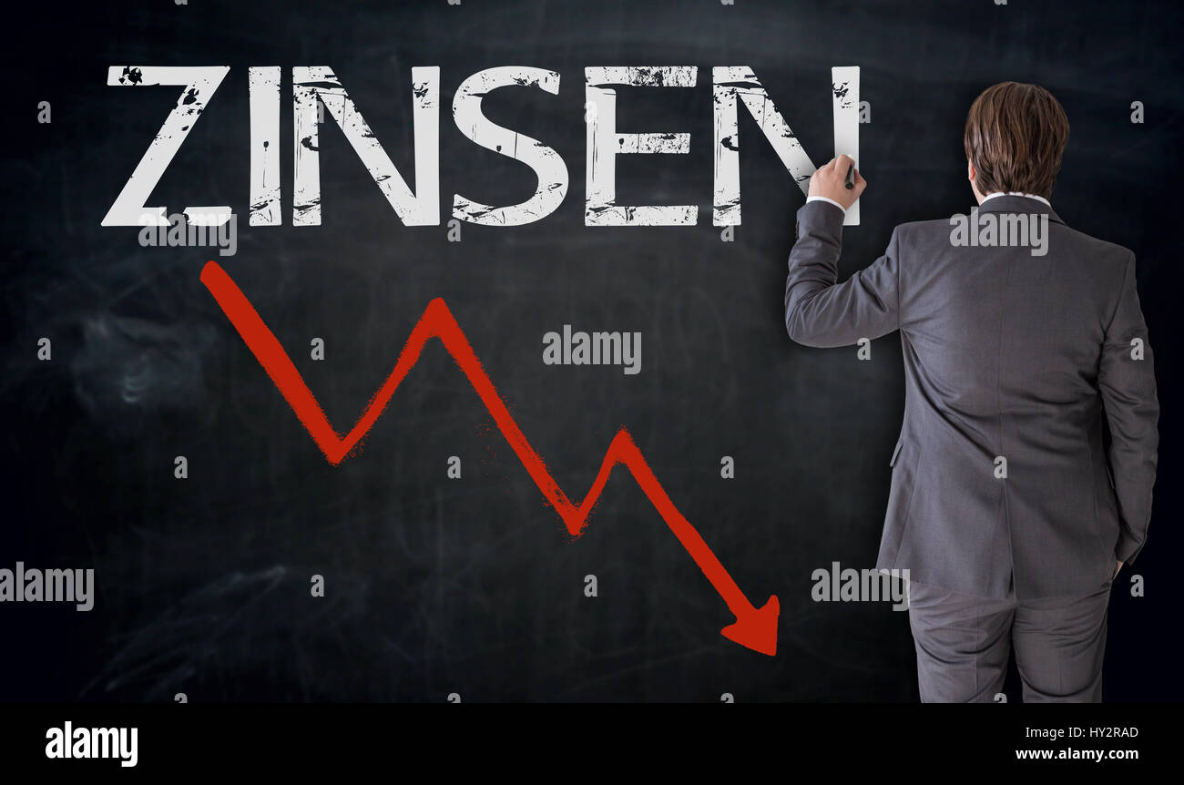 Geschäftsmann schreibt Zinsen (in deutscher Sprache) auf Tafel Konzept. Stockfoto