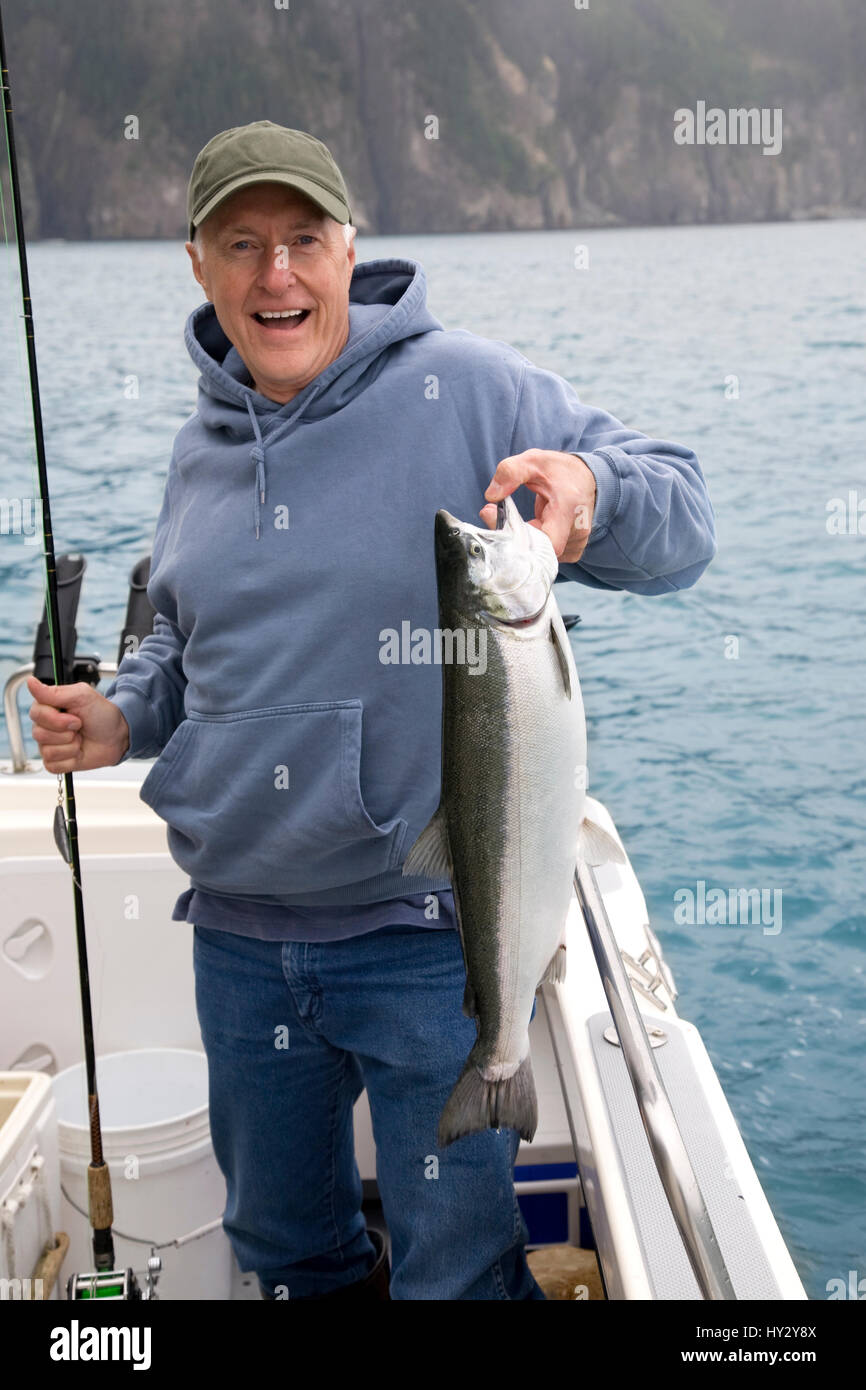 Ein glücklicher Fischer in Alaska hält ein frisch gefangener Silberlachs Stockfoto