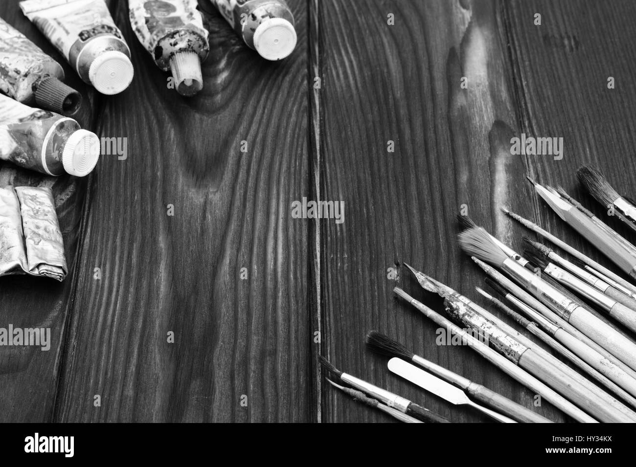 Pinsel und Farben sind auf dunklen Holzfläche verteilt Stockfoto