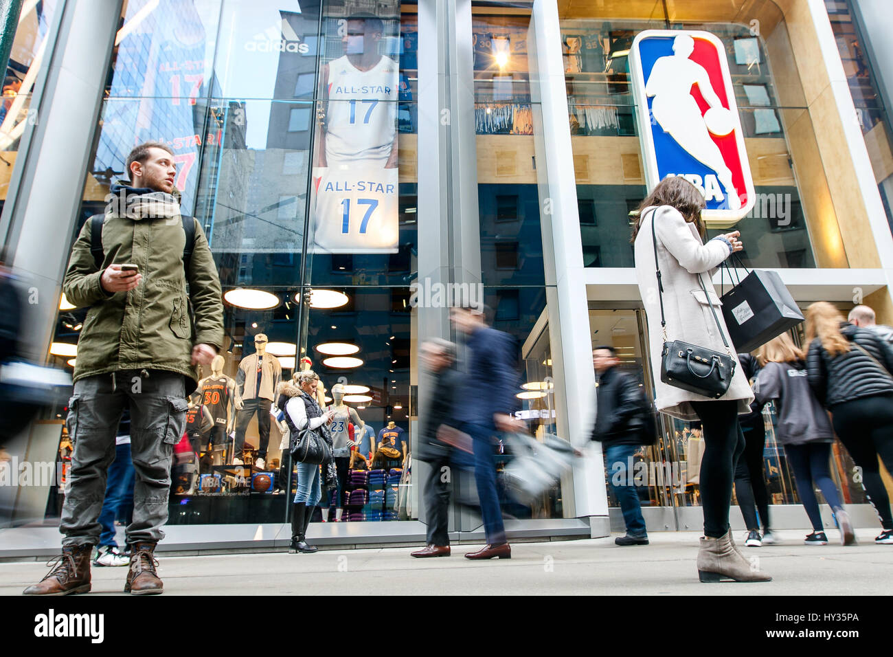 Die Leute stehen und gehen durch die Frontscheibe des NBA Store in Manhattan. Stockfoto