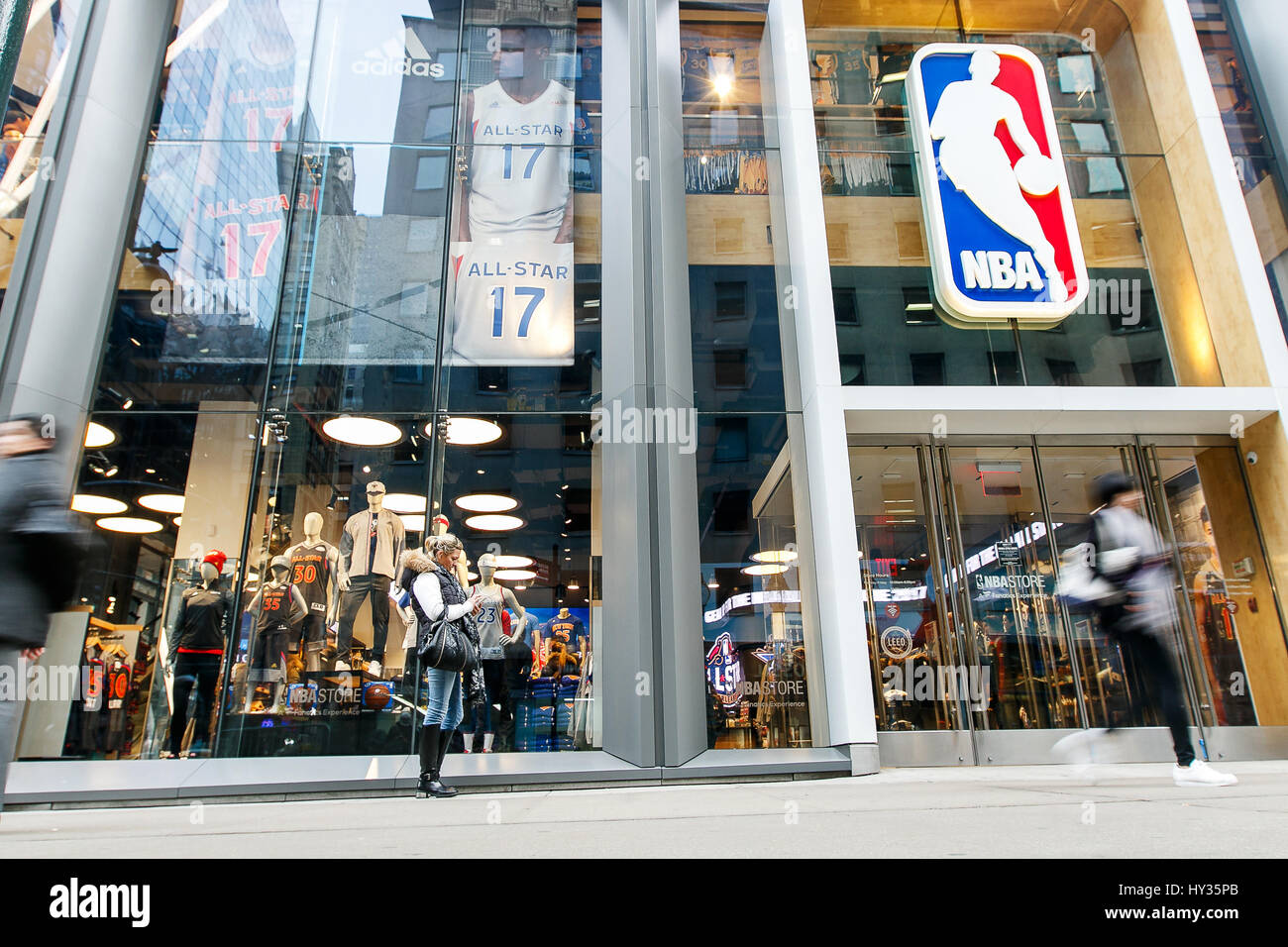 Die Leute stehen und gehen durch die Frontscheibe des NBA Store in Manhattan. Stockfoto