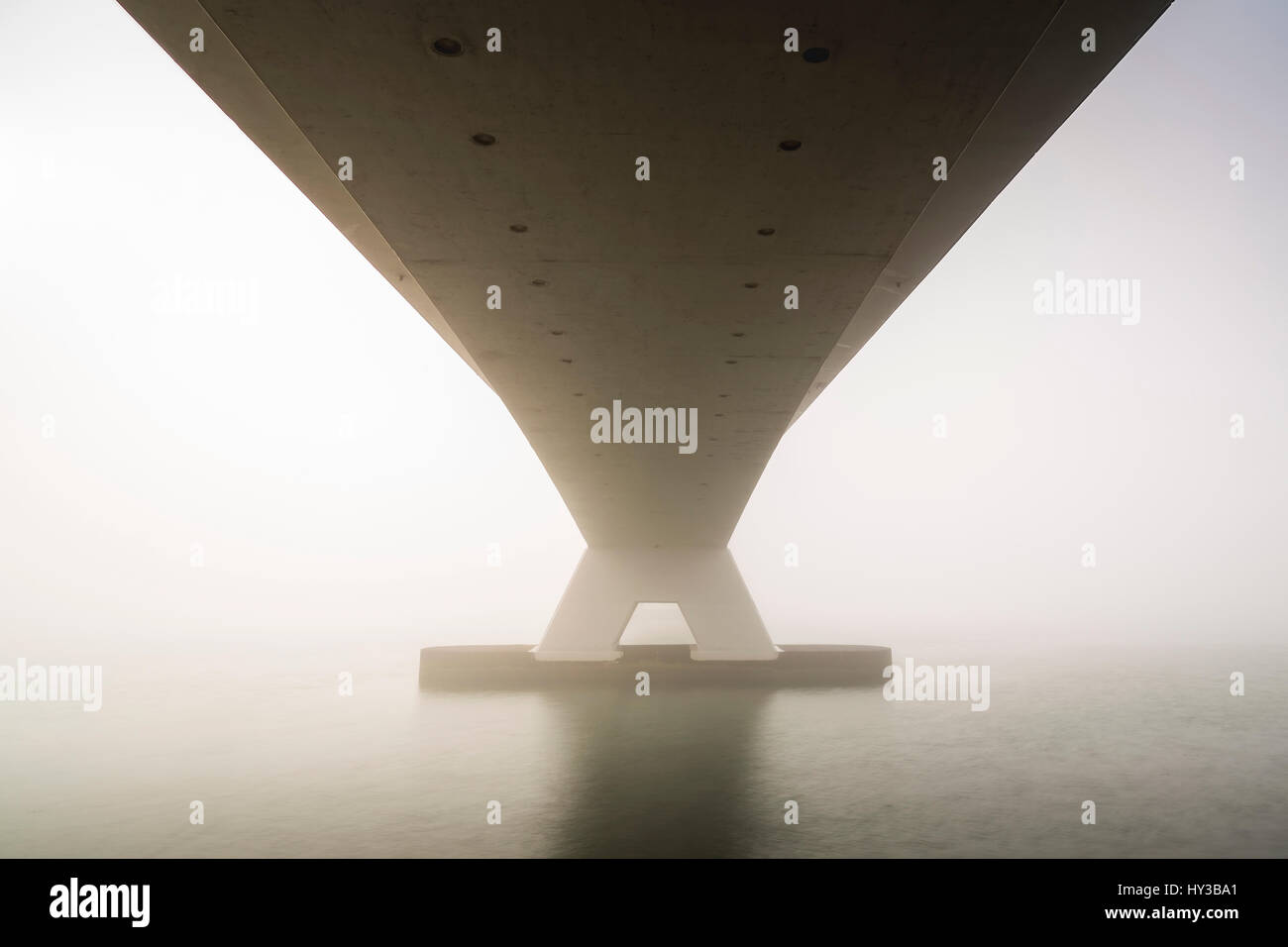 Zeeland-Brücke (Zeelandbrug) in Nebel bei Sonnenaufgang im Winter abgedeckt. Niedrige Visibilty macht die Sonne durch den Nebel der Zeeland-Brücke ist die Liebe Stockfoto