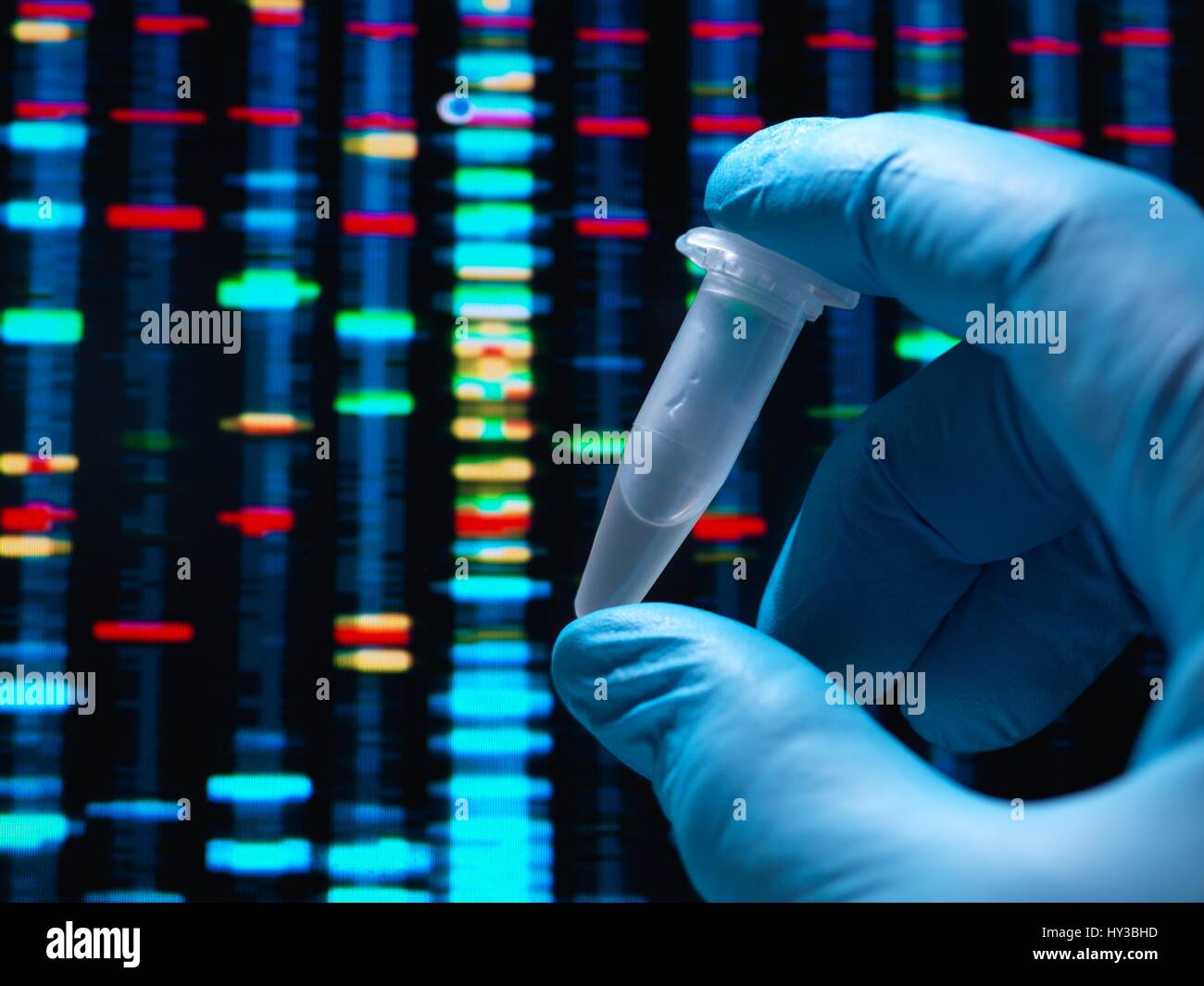 Wissenschaftler halten ein Fläschchen mit einer DNA (Desoxyribonukleinsäure) Probe bereit für Gentests, mit DNA-Testergebnisse auf einem Bildschirm. Stockfoto