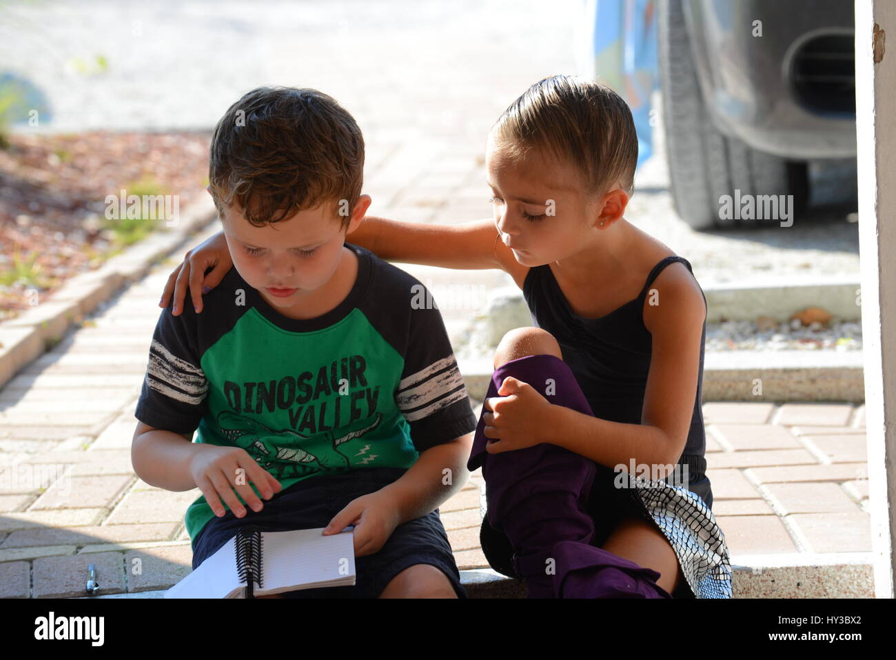 zwei Kinder ein Buch außerhalb Stockfoto