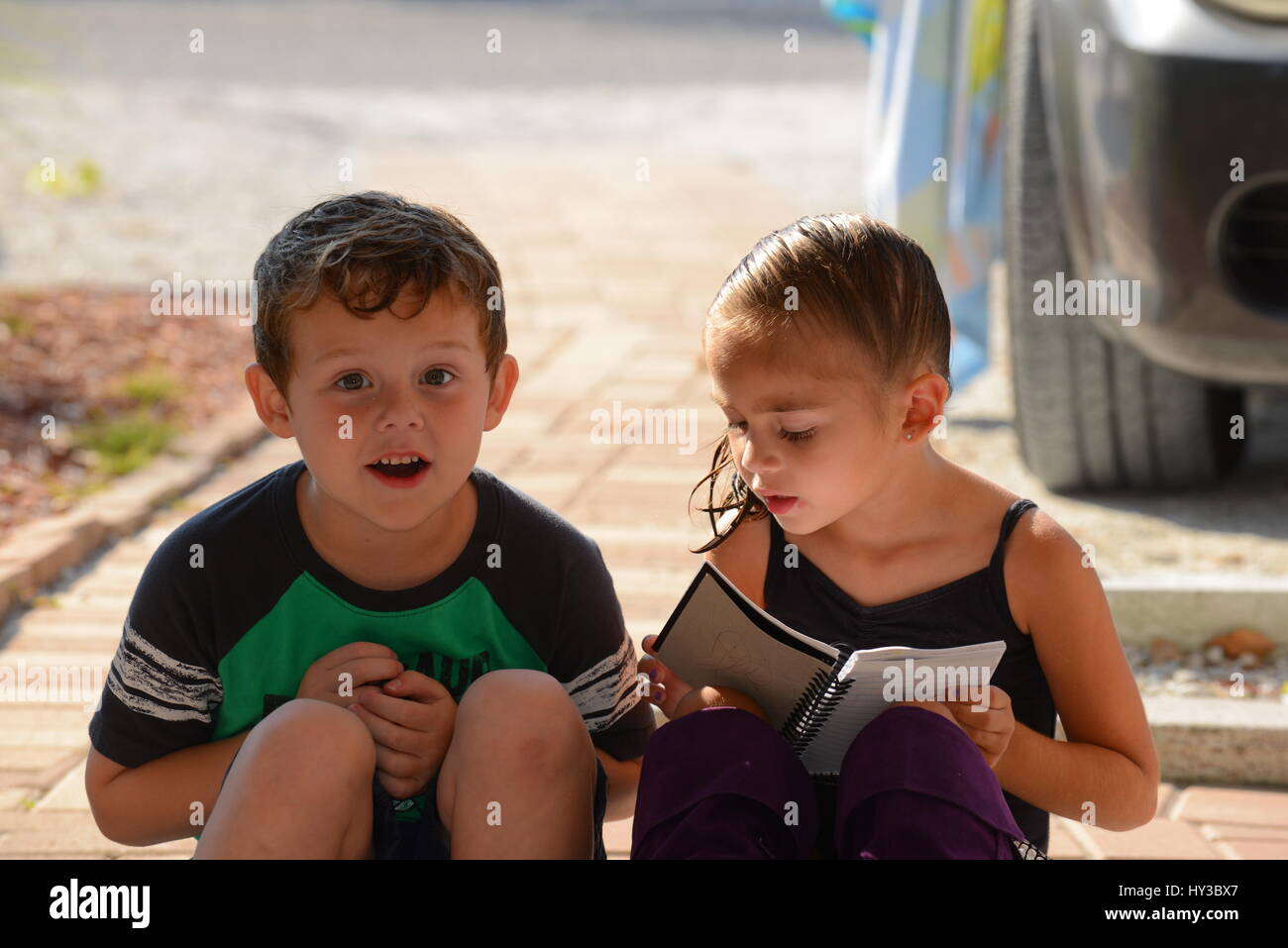 zwei Kinder lesen ein Buch Standortwahl außerhalb Stockfoto