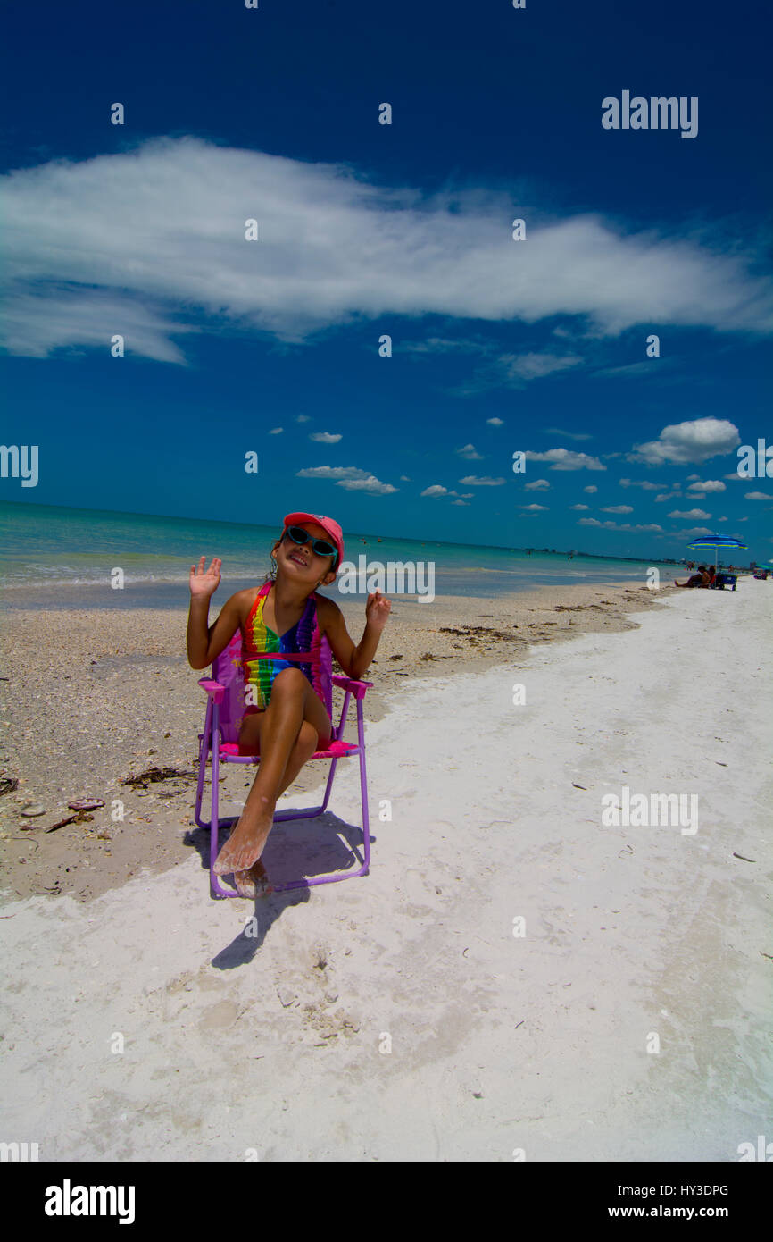 junges Mädchen am Strand sitzen in ihrem Strand Stuhl posiert Stockfoto