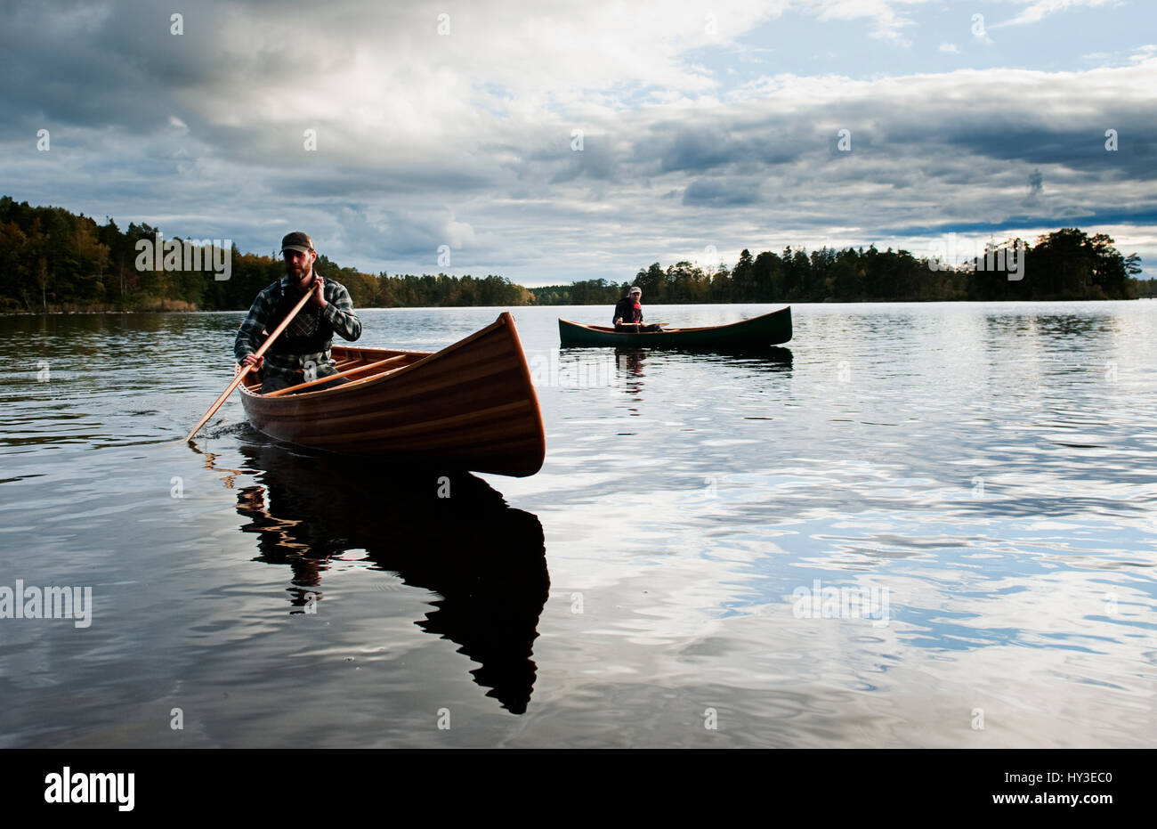 Schweden, Smaland, reife Männer in Booten auf See, umgeben von Wald Stockfoto