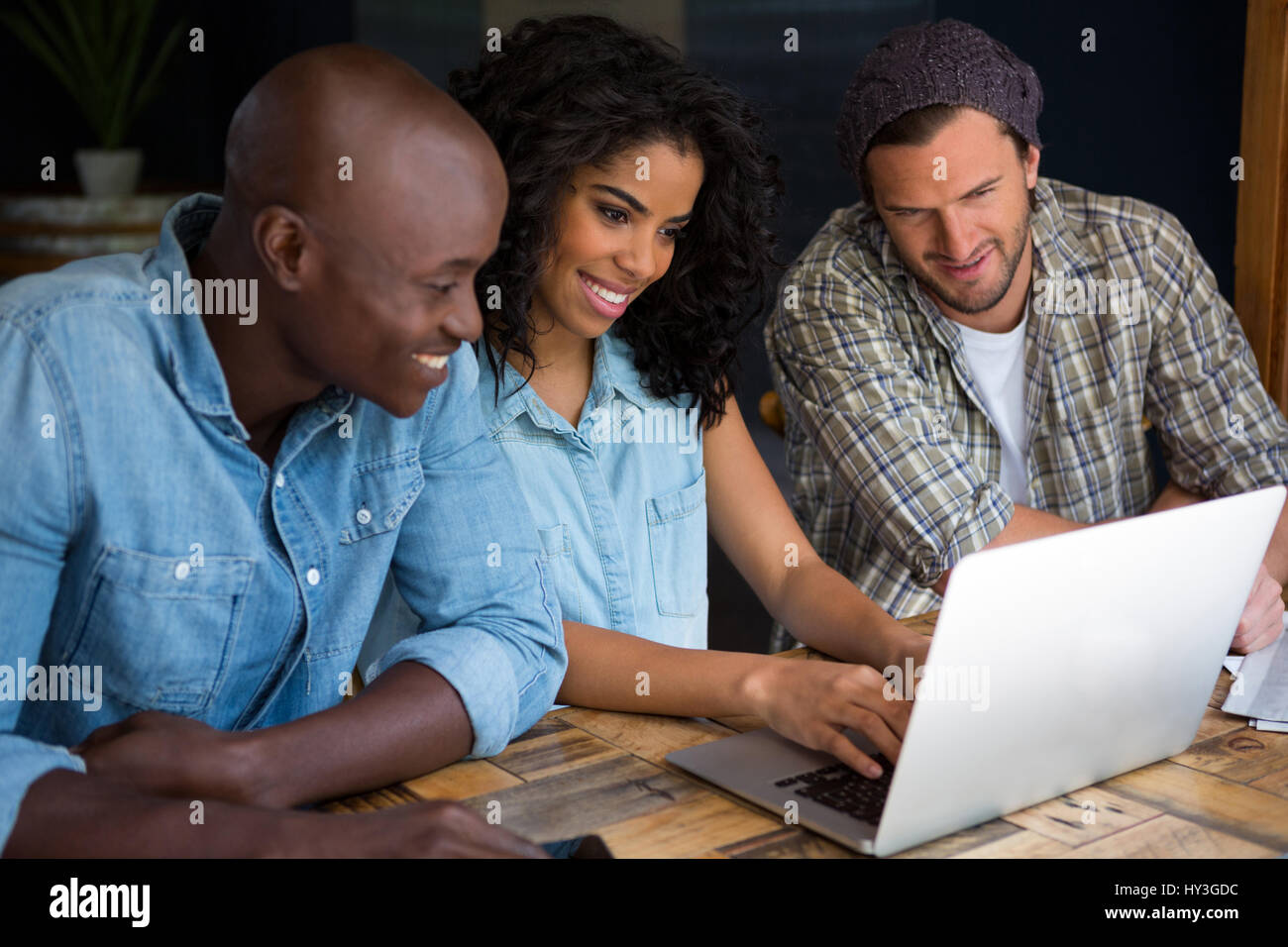 Glückliche Freunde mit Laptop am Holztisch in Coffee-shop Stockfoto