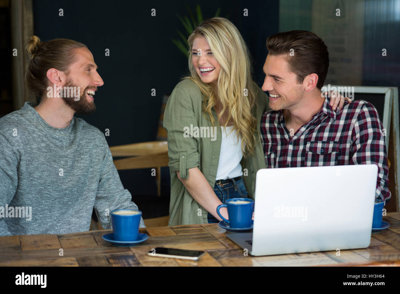Fröhliche junge männliche und weibliche Freunde reden in Coffee-shop Stockfoto