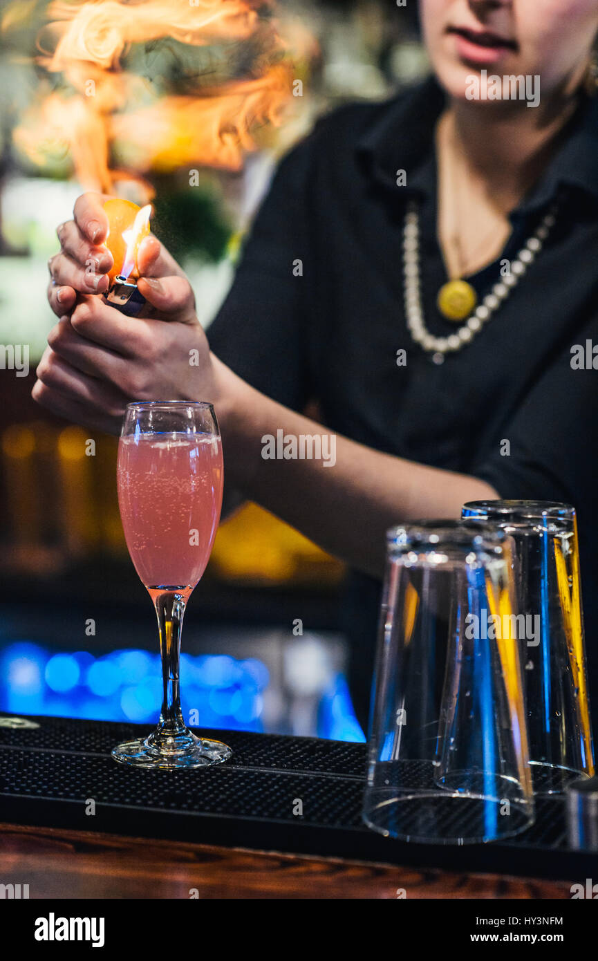 Kellnerin Flaming eine Orangenhaut bei der Herstellung einer Französisch-Martini Stockfoto