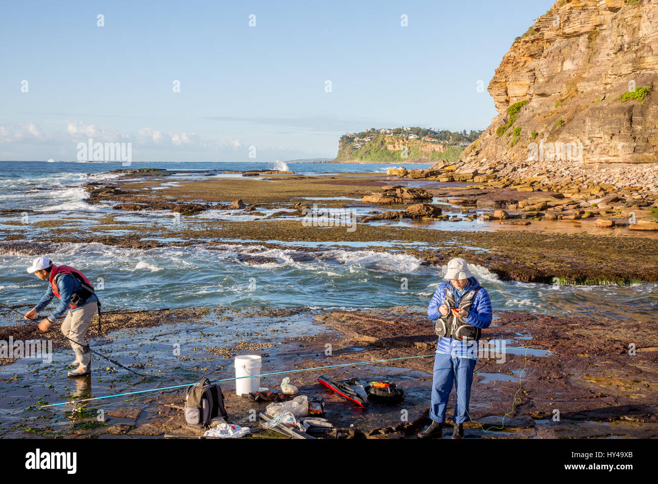 Asiatische Männer Felsenfischen am Bilgola Beach in Sydney, NSW, Australien mit Schwimmweste. Stockfoto