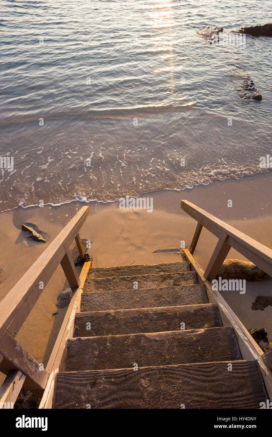 Privater Zugang zu einem öffentlichen Strand auf Oahu Hawaii bei Sonnenuntergang mit der Treppe im Mittelpunkt und das Wasser heraus verwischt. Stockfoto
