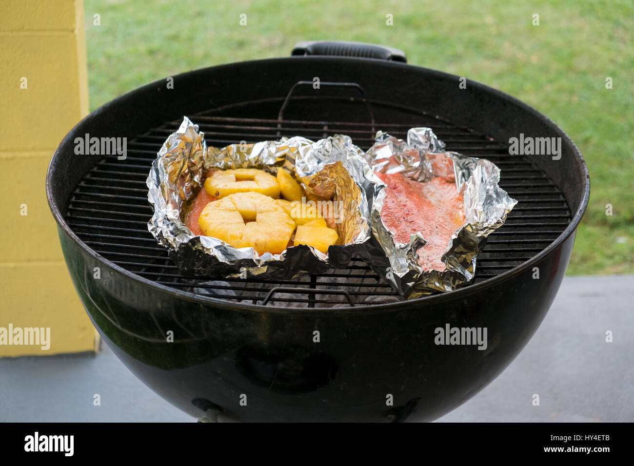 Holzkohle-Grill mit Lachs und Ananas über glühende Kohlen auf dem Grill in Oahu Hawaii. Stockfoto