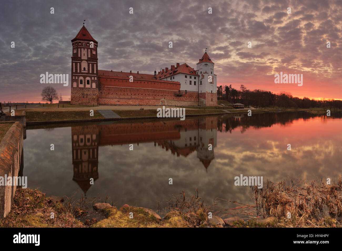 Alte Burg bei Sonnenuntergang. Schönen Abend Sonnenuntergang über Mirsky Burg. Reflexion der Burg und bunten Himmel in See. Schöne historische Hinterg Stockfoto