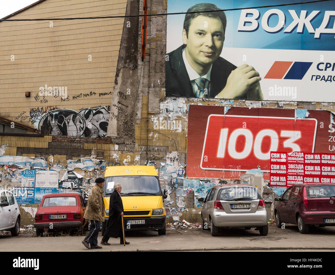 Belgrad, Serbien - 8. März 2015: alte Menschen zu Fuß vor der Propaganda Poster für den Ministerpräsidenten Aleksandar vucic Bild von Fußgängern w Stockfoto