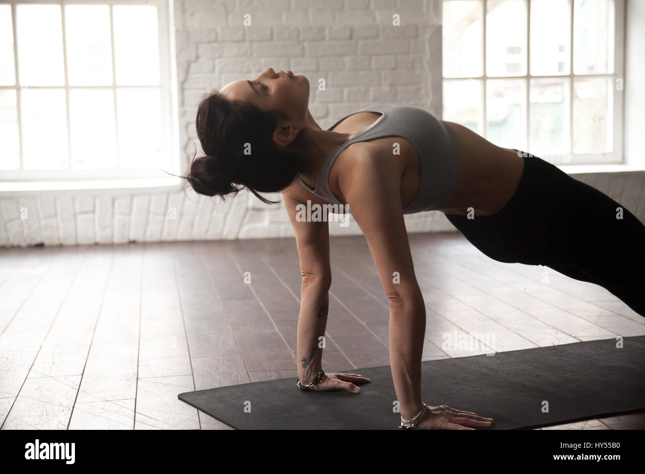 Junge attraktive Frau in Purvottanasana pose, weiße Loft-studio Stockfoto