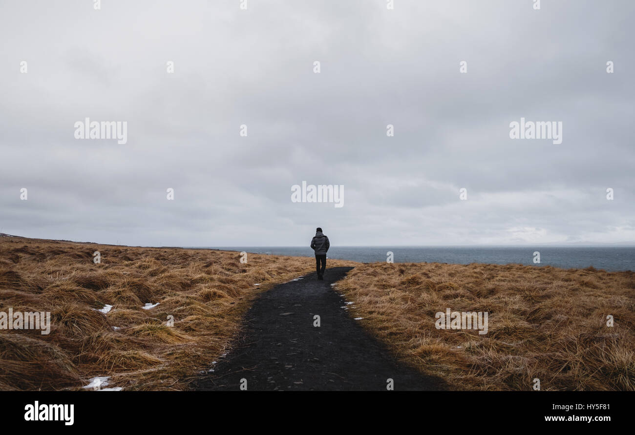 Hinten einen Mann allein zu Fuß auf Fußweg in getrockneten Feld anzeigen Stockfoto