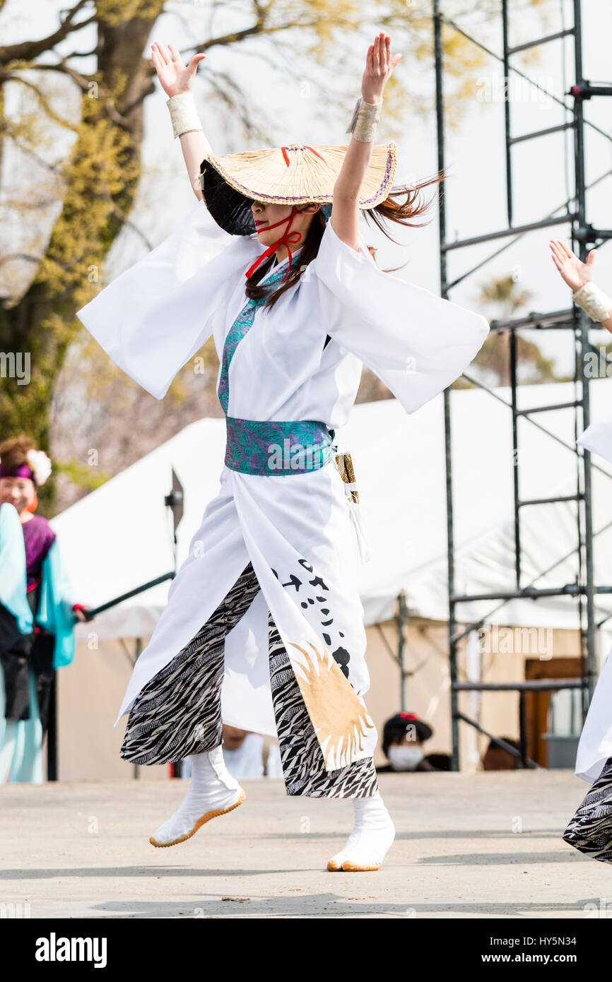 Hinokuni Yosakoi Dance Festival. Frau Tänzer tanzen auf der Bühne und halten nakuro, hölzerne Klöppel. Trägt weiße Yukata und Stroh Landwirt hat. Stockfoto