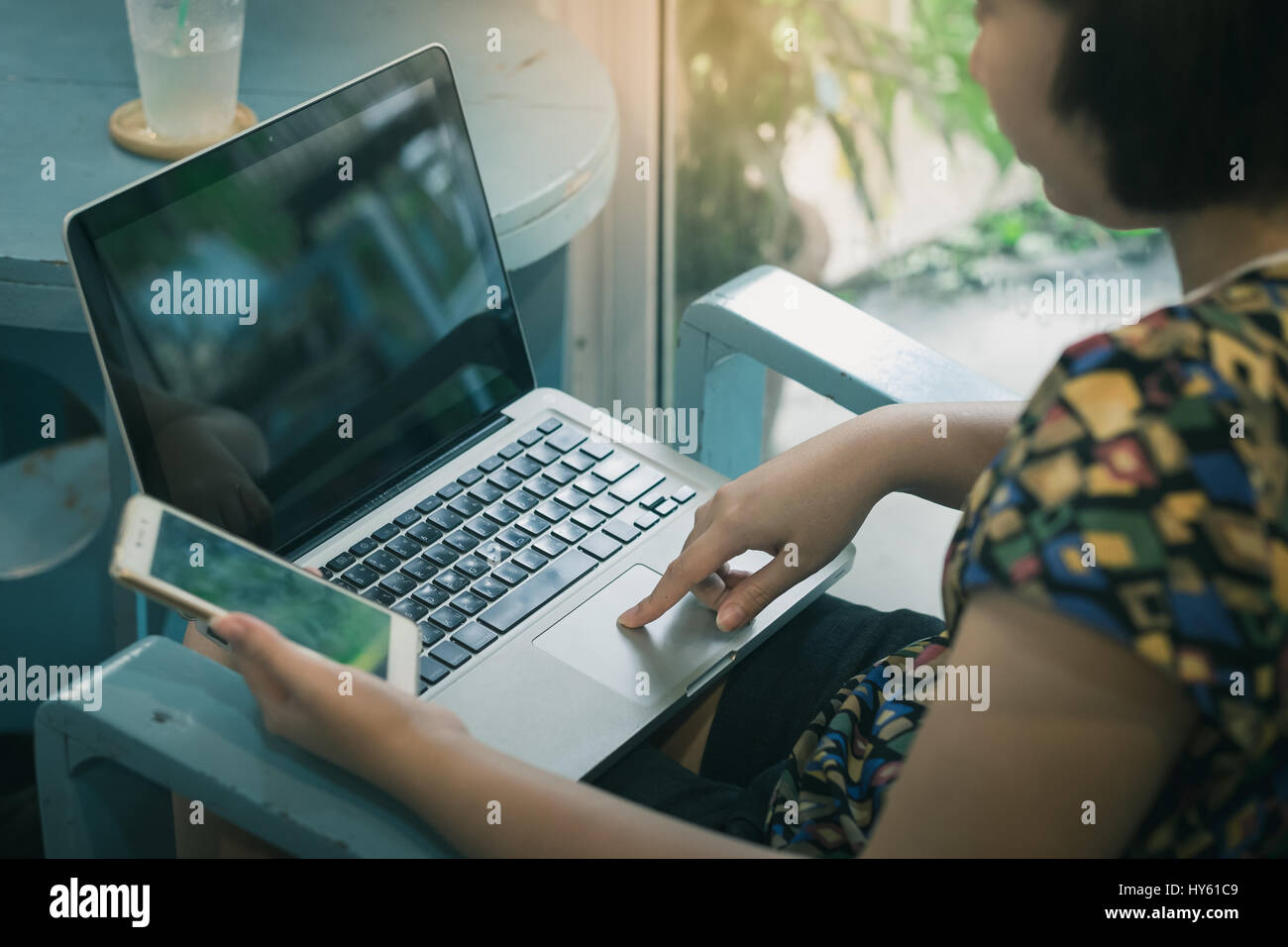 Frau Zeigefinger drücken Sie die Taste auf Laptop-Computer, während eine andere Hand mit Smartphone für den elektronischen Einkauf. E-Commerce-Geschäft bei Wohnkonzept wi Stockfoto